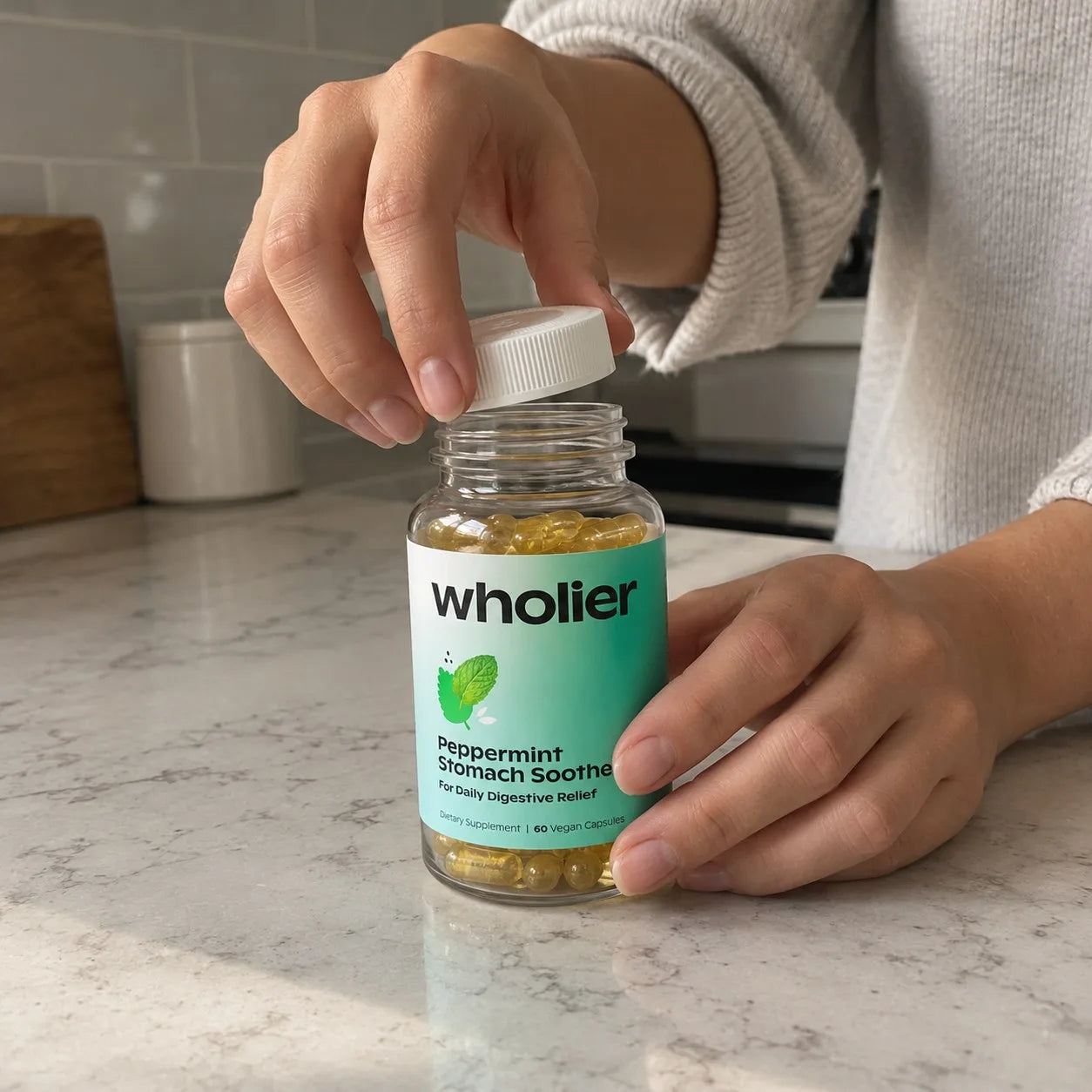 Hands opening a bottle of wholier Peppermint Stomach Soother on a kitchen counter