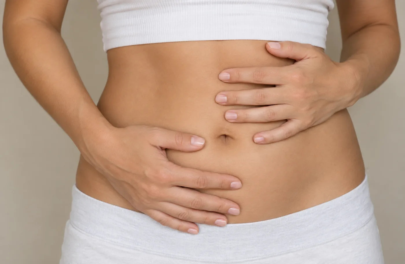 Close-up of a woman holding both hands on her bloated stomach