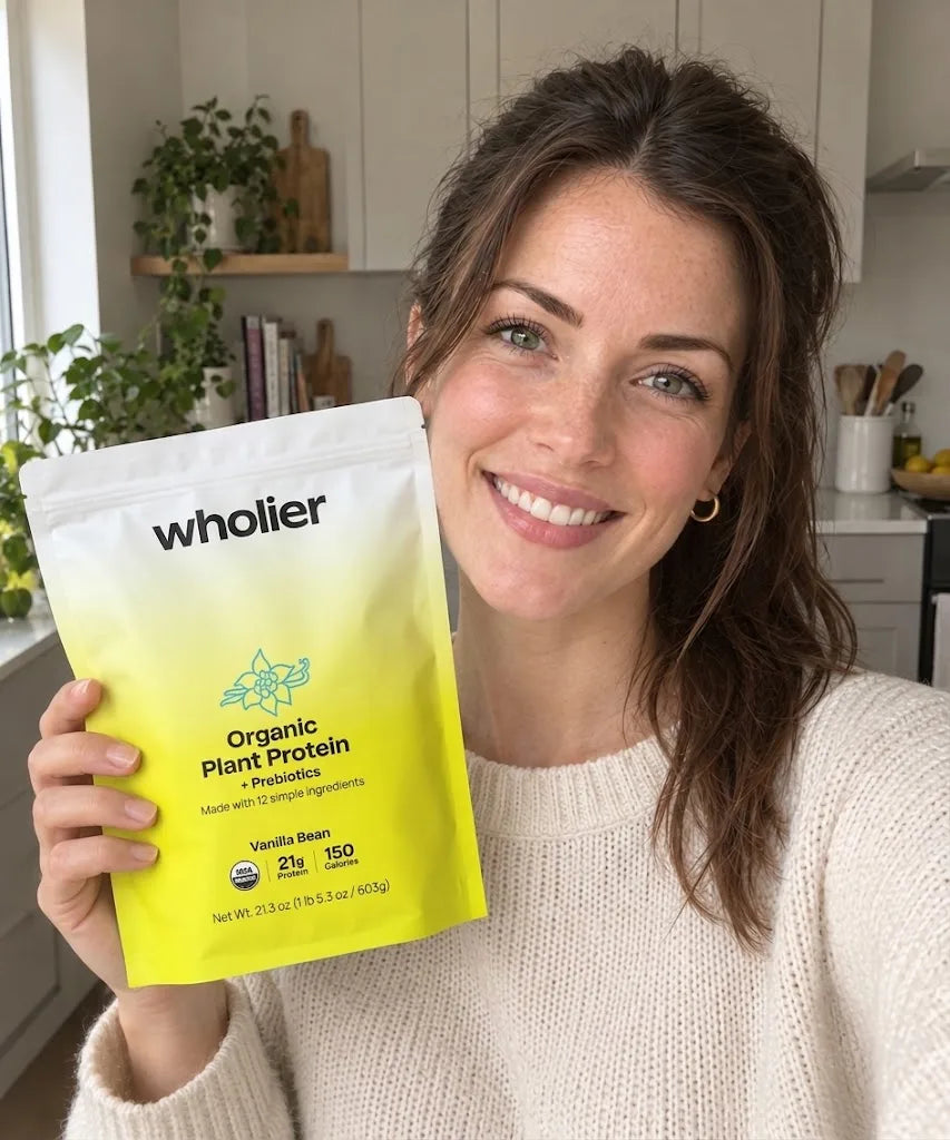 Sarah smiling and holding a pouch of wholier Organic Plant Protein in Vanilla Bean