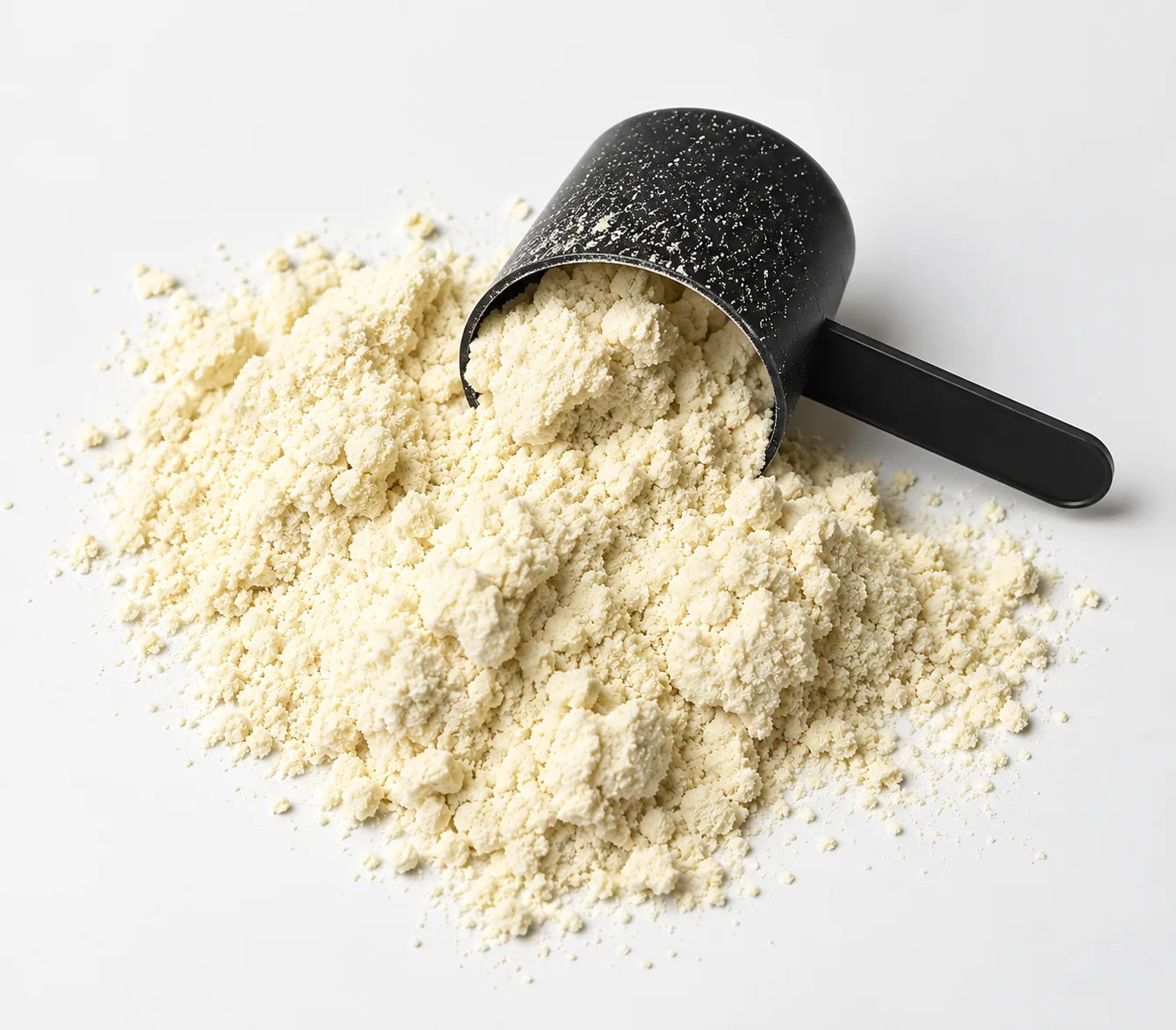 A black scoop of whey protein powder spilled on a white surface